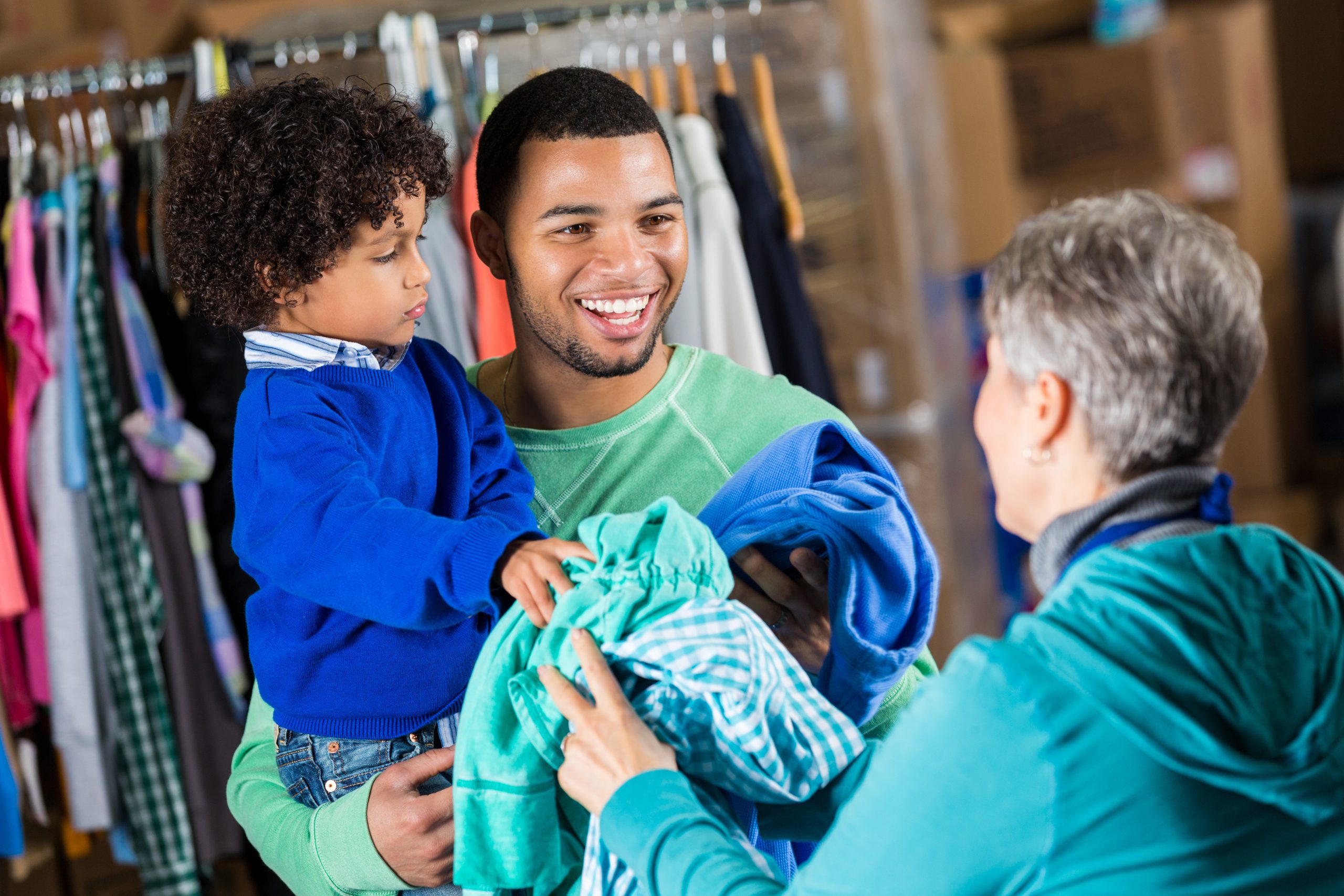 Father and son donating clothing to charity distribution warehouse